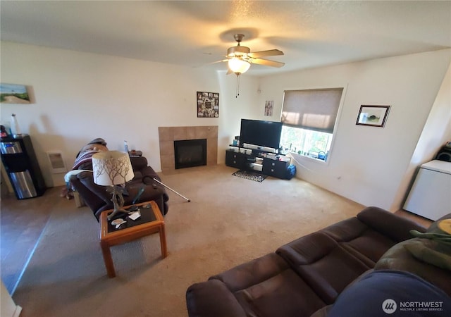 living area with a ceiling fan, carpet flooring, and a tiled fireplace