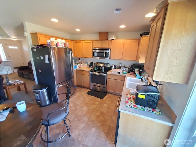 kitchen with light brown cabinets, stainless steel appliances, light countertops, and a sink