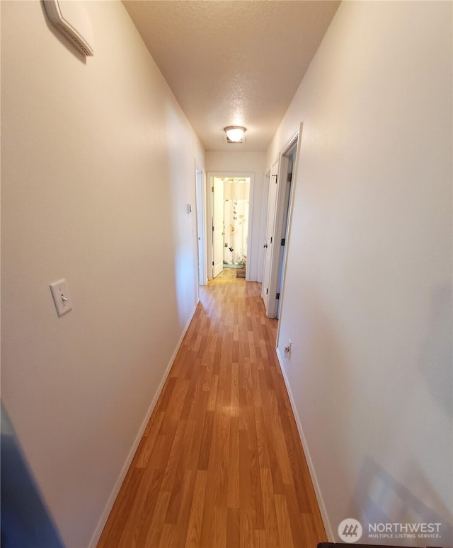 hall with light wood-style flooring and baseboards