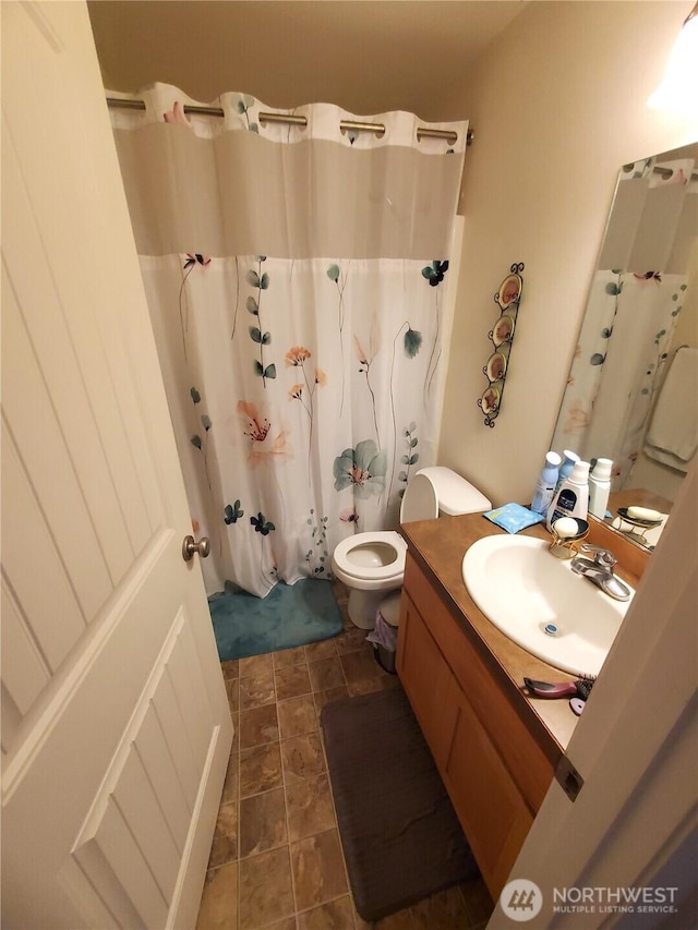 bathroom with vanity, stone finish flooring, and toilet