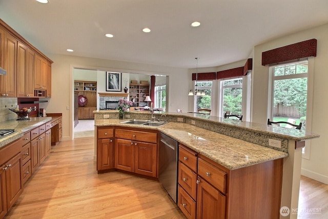 kitchen featuring stainless steel appliances, a sink, light wood finished floors, brown cabinetry, and recessed lighting