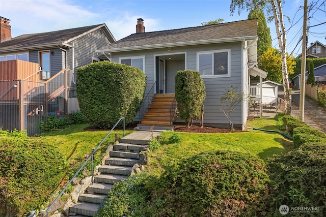 view of front of property with fence, a chimney, stairs, and a front yard