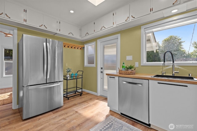 kitchen with a sink, light wood-style flooring, stainless steel appliances, recessed lighting, and white cabinetry