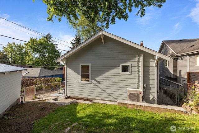 rear view of house with fence, a gate, ac unit, and a yard