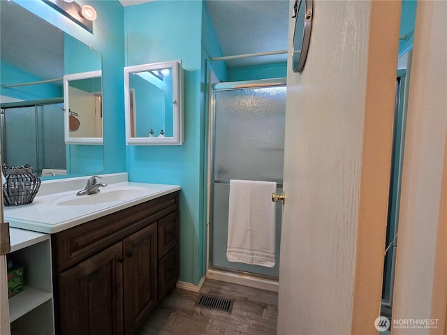 bathroom with visible vents, a stall shower, wood finished floors, and vanity