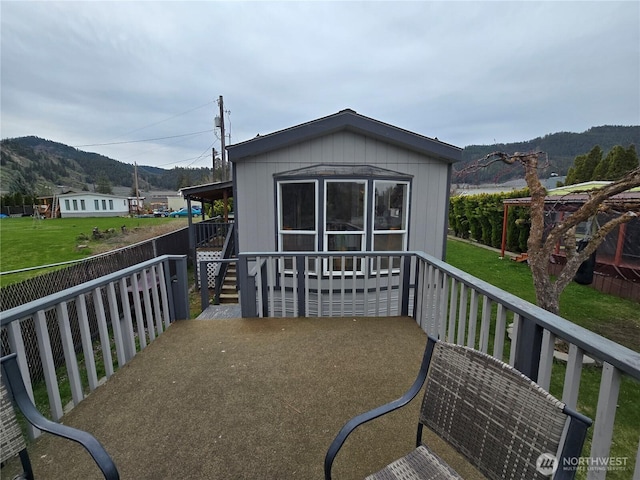 rear view of house featuring a yard, a mountain view, and fence