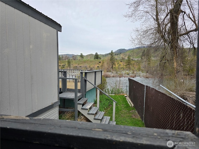 view of yard featuring a deck with water view and fence