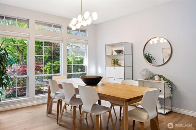 dining space featuring baseboards, light wood finished floors, and a notable chandelier