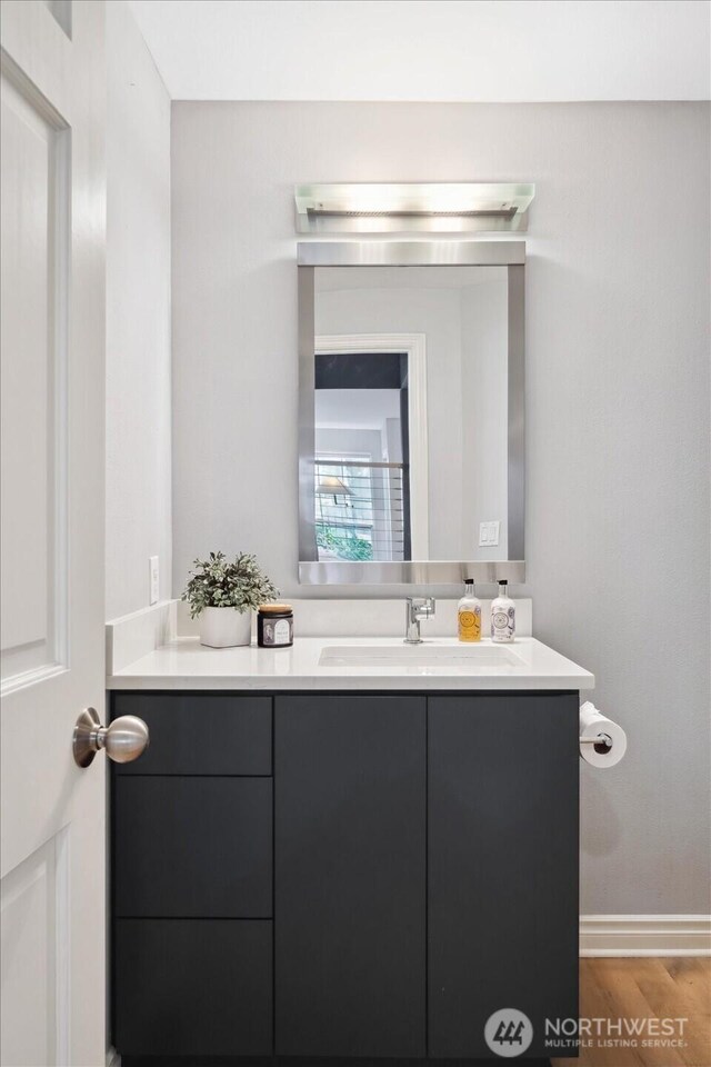bathroom featuring baseboards, wood finished floors, and vanity