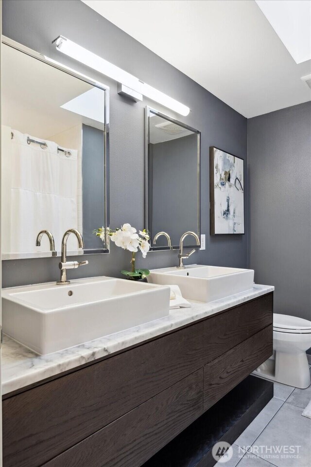 bathroom with double vanity, toilet, a shower with curtain, and a sink