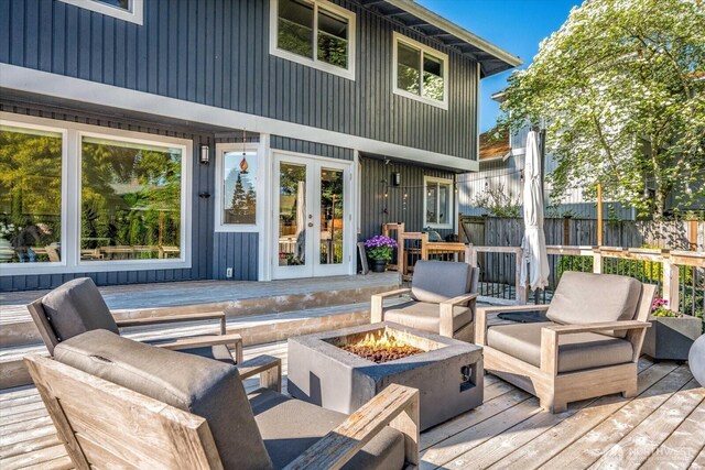 wooden terrace with fence, french doors, and an outdoor living space with a fire pit