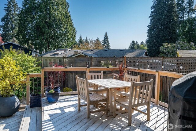 wooden deck featuring outdoor dining space and a grill