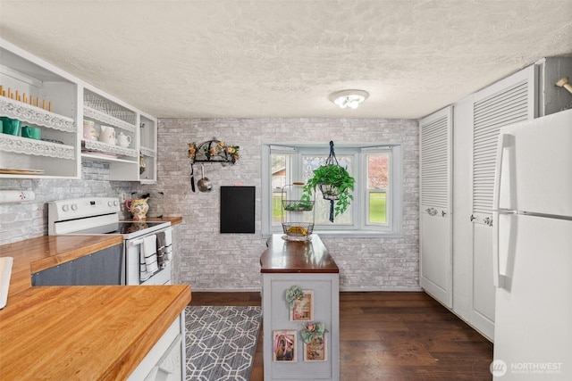 kitchen featuring dark wood finished floors, white appliances, butcher block counters, a textured ceiling, and brick wall