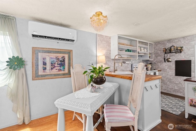 dining room with an AC wall unit, baseboards, and wood finished floors
