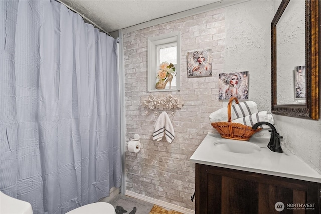bathroom with brick wall, vanity, a textured ceiling, and curtained shower