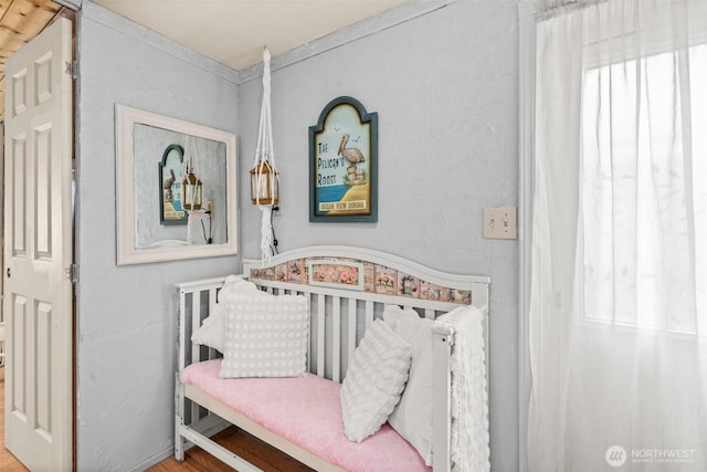 bedroom with a nursery area and wood finished floors