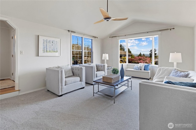 living room with ceiling fan, arched walkways, carpet floors, baseboards, and lofted ceiling
