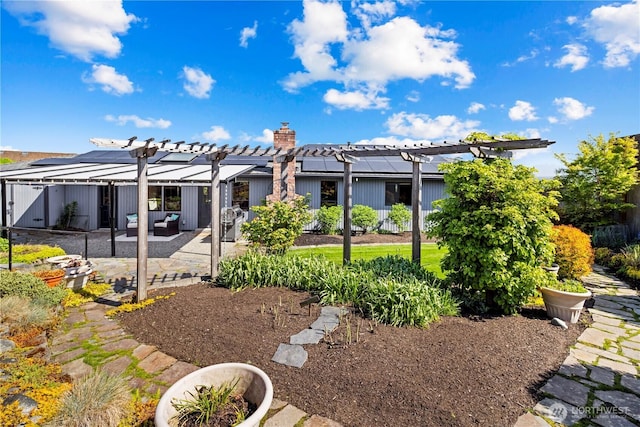 rear view of house featuring fence, a pergola, a chimney, a patio area, and solar panels