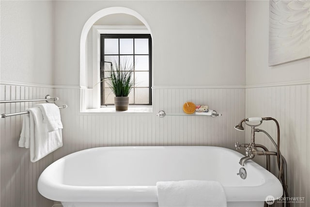 full bath featuring a freestanding bath and a wainscoted wall