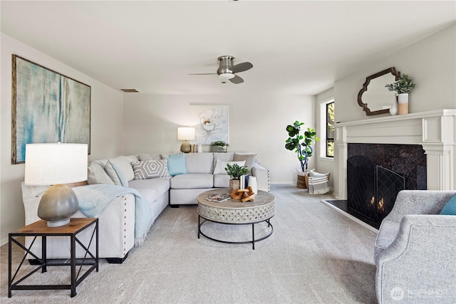 living area with carpet flooring, a premium fireplace, a ceiling fan, baseboards, and visible vents