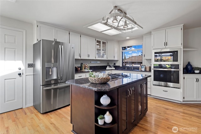 kitchen with white cabinets, open shelves, appliances with stainless steel finishes, and a sink