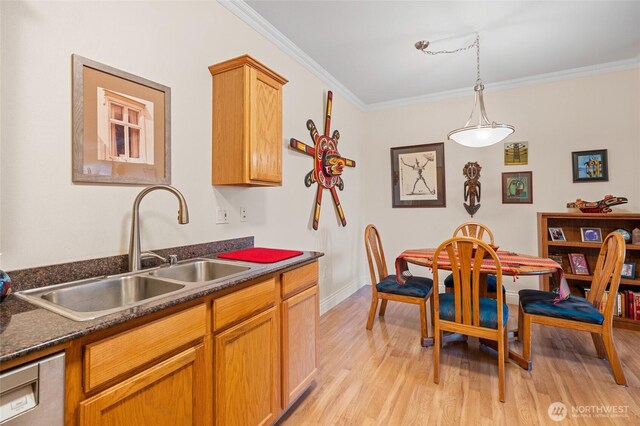 kitchen featuring a sink, dark countertops, ornamental molding, and light wood-style floors