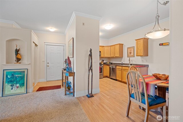 kitchen featuring crown molding, a sink, light wood-style floors, stainless steel appliances, and baseboards