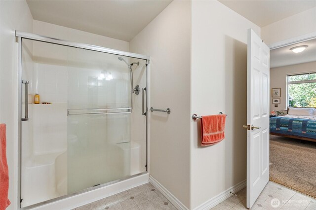 bathroom featuring connected bathroom, baseboards, and a stall shower