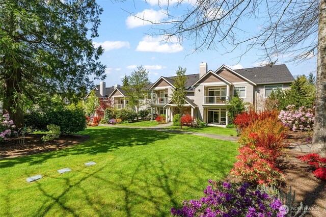 exterior space featuring a chimney, a front lawn, and a balcony