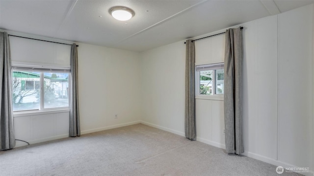 spare room with light carpet and baseboards