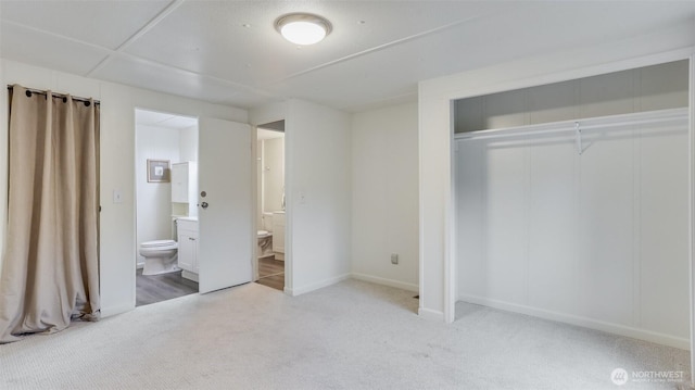 unfurnished bedroom with light carpet, a closet, connected bathroom, and baseboards