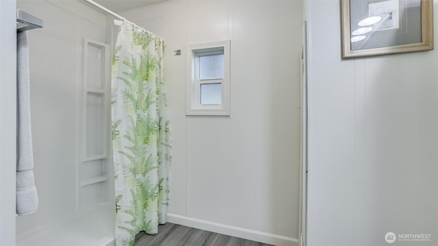 bathroom featuring curtained shower, baseboards, and wood finished floors