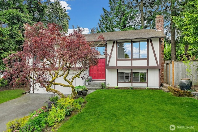 english style home featuring driveway, a chimney, an attached garage, and stucco siding