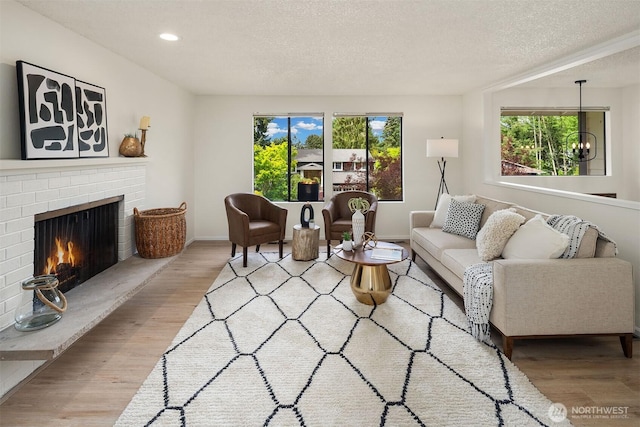 living area with wood finished floors, a textured ceiling, a fireplace, recessed lighting, and baseboards