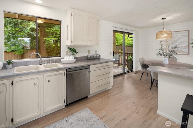 kitchen with dishwasher, a sink, white cabinetry, light wood-type flooring, and decorative light fixtures