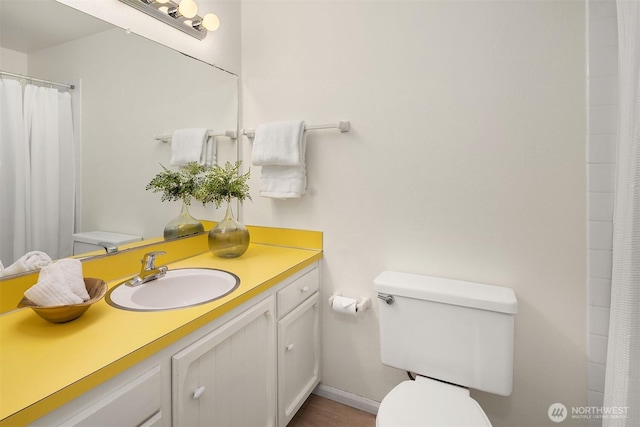 bathroom with toilet, vanity, and baseboards