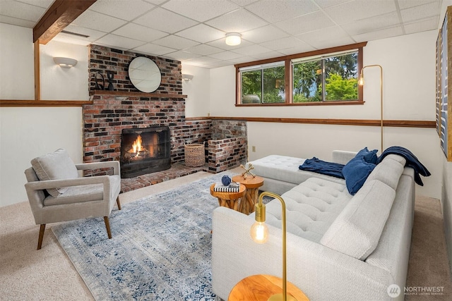 living area featuring carpet flooring, a drop ceiling, and a brick fireplace