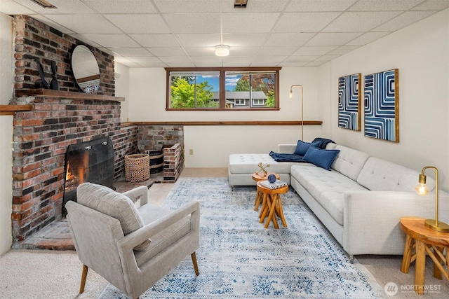 living room featuring a paneled ceiling, a brick fireplace, and carpet flooring