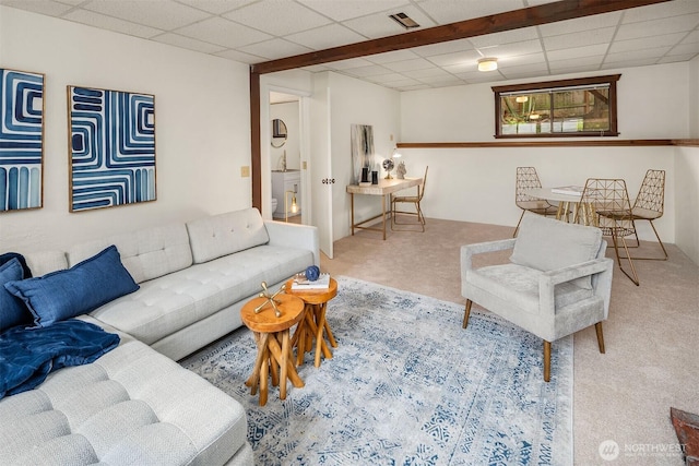 carpeted living area with a paneled ceiling