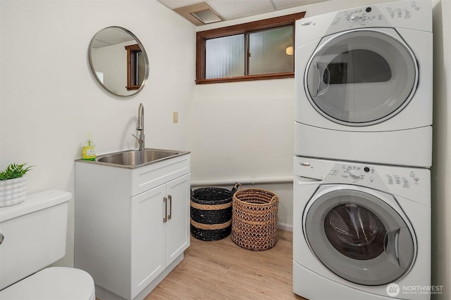 washroom with stacked washing machine and dryer and light wood finished floors