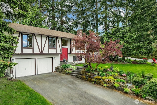 view of front of property with asphalt driveway, a chimney, an attached garage, and a front lawn