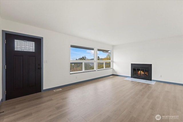 9360 SE Southworth Dr, Port Orchard, WA 98366 - unfurnished living room featuring light wood-style flooring, baseboards, and a fireplace with flush hearth