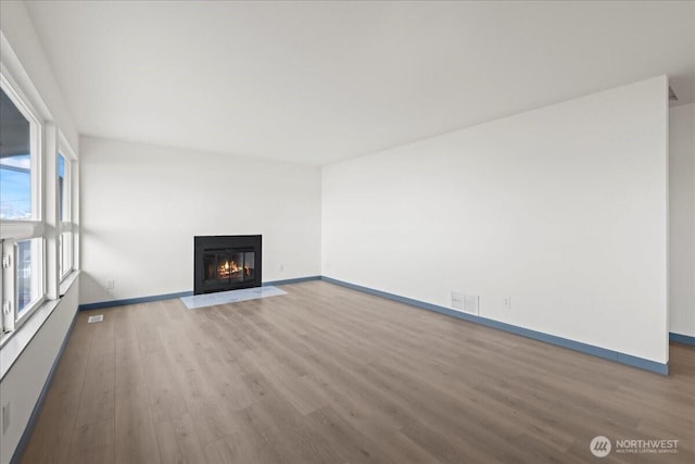 9360 SE Southworth Dr, Port Orchard, WA 98366 - unfurnished living room featuring visible vents, baseboards, wood finished floors, and a fireplace with flush hearth