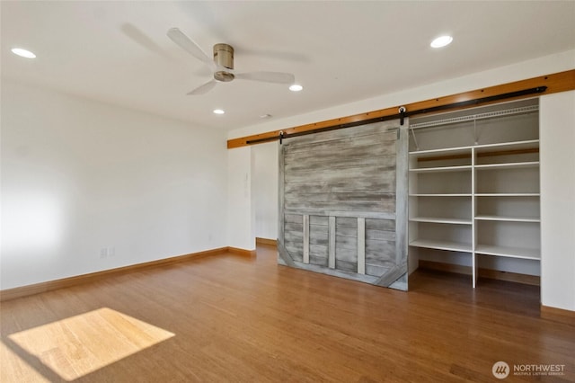 8996 Dearborn Ave, Blaine, WA 98230 - unfurnished bedroom with a ceiling fan, a barn door, wood finished floors, baseboards, and recessed lighting