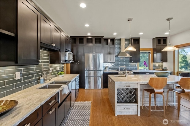 8996 Dearborn Ave, Blaine, WA 98230 - kitchen featuring appliances with stainless steel finishes, a sink, wall chimney exhaust hood, backsplash, and a center island with sink
