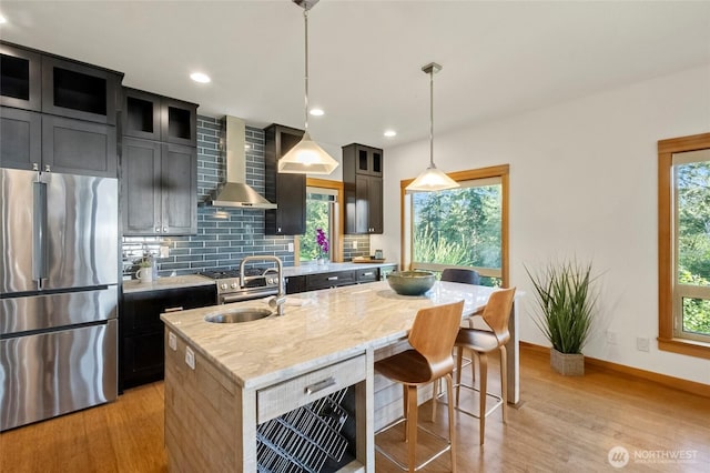 8996 Dearborn Ave, Blaine, WA 98230 - kitchen with freestanding refrigerator, light wood-style floors, a center island with sink, wall chimney exhaust hood, and a sink