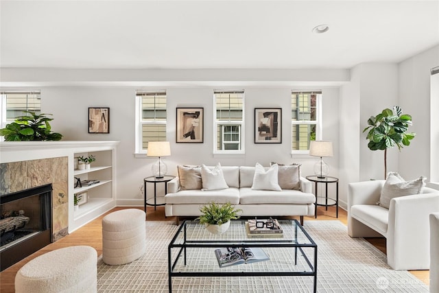 living room featuring baseboards, plenty of natural light, a fireplace, and wood finished floors