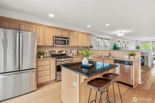 kitchen featuring a sink, appliances with stainless steel finishes, light brown cabinets, and a peninsula