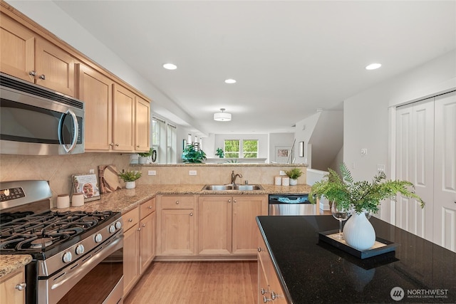 kitchen with light brown cabinetry, tasteful backsplash, a sink, light wood-style floors, and stainless steel appliances