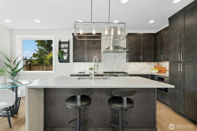 10284 133rd Ct NE, Redmond, WA 98033 - kitchen featuring wall chimney range hood, a sink, light wood finished floors, a breakfast bar, and recessed lighting